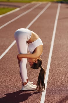 Side view. Young woman in sportive clothes is exercising outdoors.