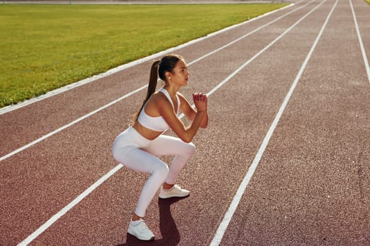 Active young woman in sportive clothes is exercising outdoors.