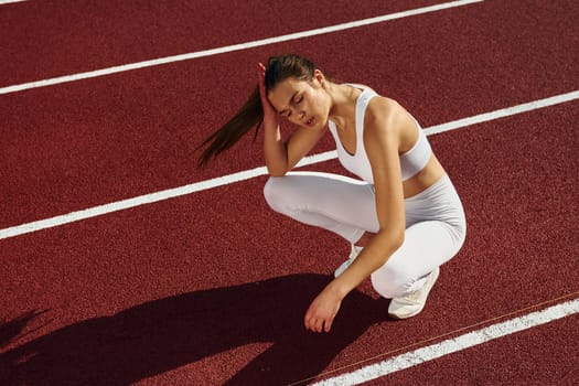 Sitting and taking a break. Young woman in sportive clothes is exercising outdoors.