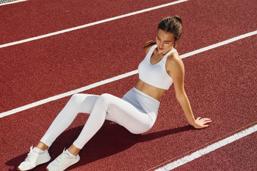 Sitting and taking a break. Young woman in sportive clothes is exercising outdoors.