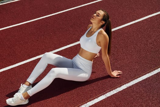 Tired, taking break. Young woman in sportive clothes is exercising outdoors.