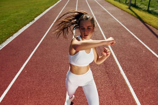 Practicing fight techniques. Young woman in sportive clothes is exercising outdoors.