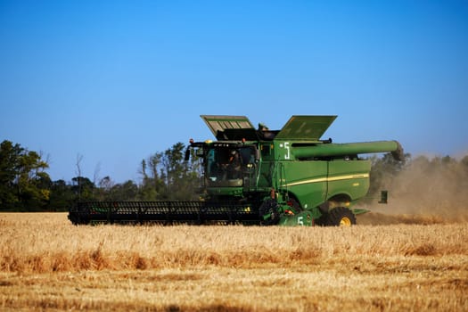 John Deere harvester works in the field. Combine Harvesting Wheat. Field field of cereals during harvesting. Modern equipment works. 07.07.22, Rostov region, Russia.