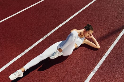 Doing abs. Young woman in sportive clothes is exercising outdoors.