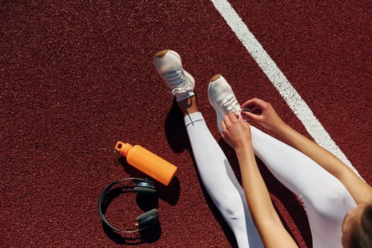 Top view of woman's legs, bottle of water and headphones.