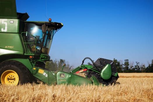 John Deere harvester works in the field. Combine Harvesting Wheat. Field field of cereals during harvesting. Modern equipment works. 07.07.22, Rostov region, Russia.