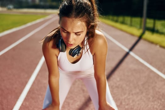 Listening to the music in headphones. Young woman in sportive clothes is exercising outdoors.