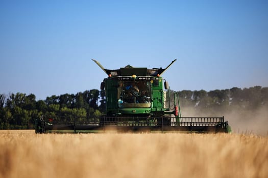 John Deere harvester works in the field. Combine Harvesting Wheat. Field field of cereals during harvesting. Modern equipment works. 07.07.22, Rostov region, Russia.