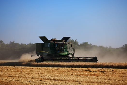 John Deere harvester works in the field. Combine Harvesting Wheat. Field field of cereals during harvesting. Modern equipment works. 07.07.22, Rostov region, Russia.