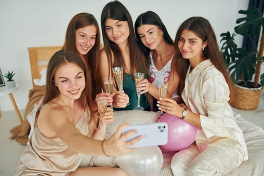Holding glasses with drink. Group of happy women that is at a bachelorette party.