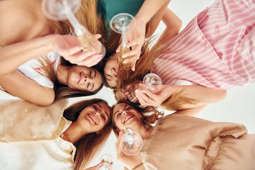Holding drinks and looking down. Group of happy women that is at a bachelorette party.