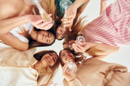 Holding drinks and looking down. Group of happy women that is at a bachelorette party.