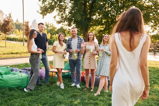 Standing with cocktails. Group of young people have a party in the park at summer daytime.