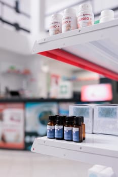 Selective focus of empty health care facility filled with shelves full with essential oil and pharmaceutical products. Drugstore space equipped with medical drugs and pills, supplement bottles.