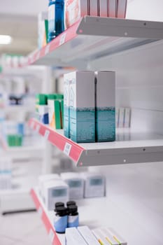 Selective focus of drugstore shelves filled with vitamins and pharmaceutical products to sell prescription medicine or treatment to customers. Empty pharmacy with medication and pills bottles.