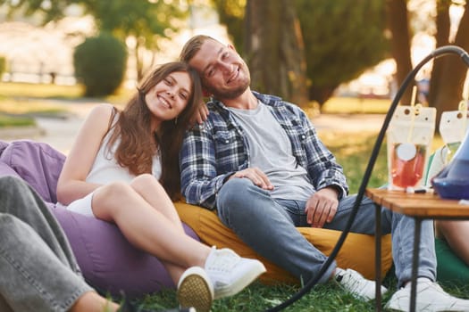 Happy couple. Group of young people have a party in the park at summer daytime.
