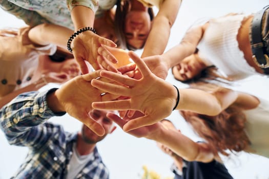 View from below of young positive people that looking down.