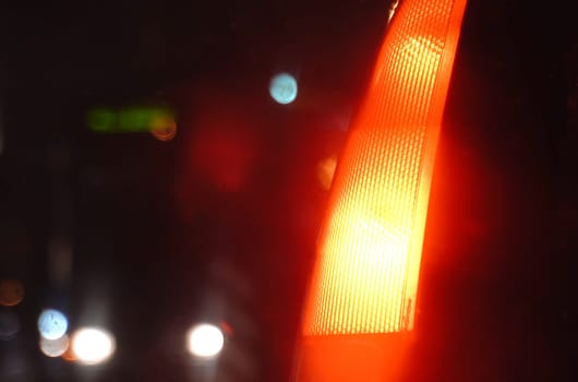 The stop signal of a passenger car burns with bright lights at night. Close-up.