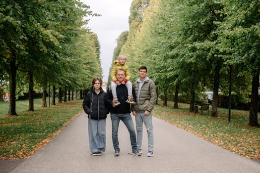 Happy family - Father with three children together in autumn park. Making it a day of fun. Parents spending time with their children outside.