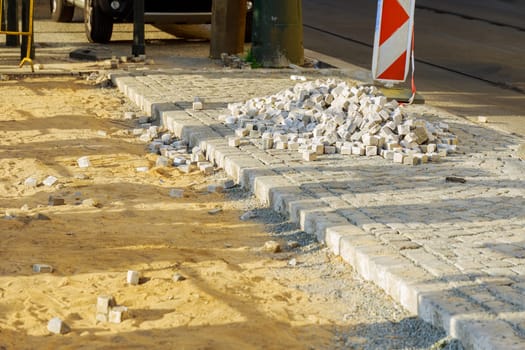 Road works to restore the pavement. Paving stones are poured on sand at the place of repair of the pavement. Arrangement of a pedestrian zone in the city. Building material.