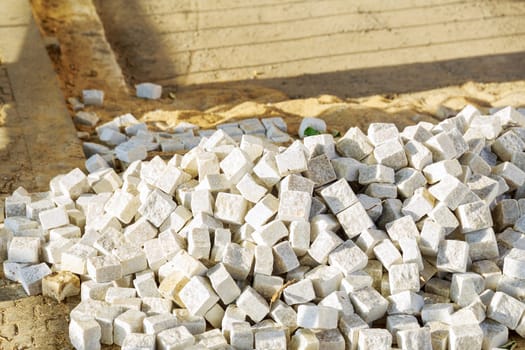 Pile of small format square white paving stones on a construction site. Arrangement of a pedestrian zone in the city.