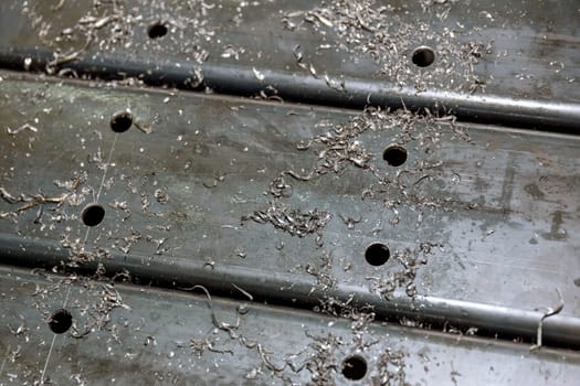 Drilled holes in metal posts for attaching various parts to the posts. Metal shavings near the holes.