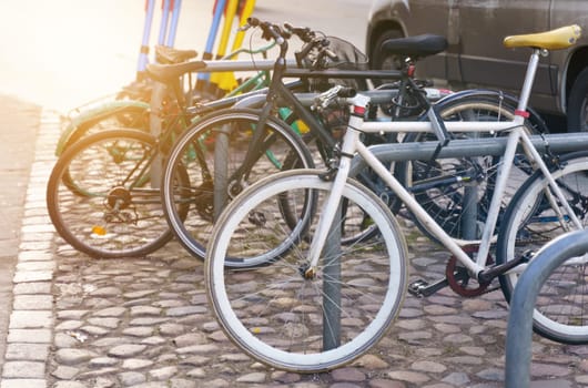 Bicycle parking in the city center on the cobblestone pavement.