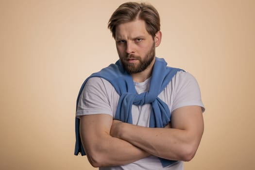 Caucasian man in t-shirt screams yell from stress tension problems feels horror hopelessness fear panic surprise shock expresses gestures rage. Handsome young guy isolated on beige studio background