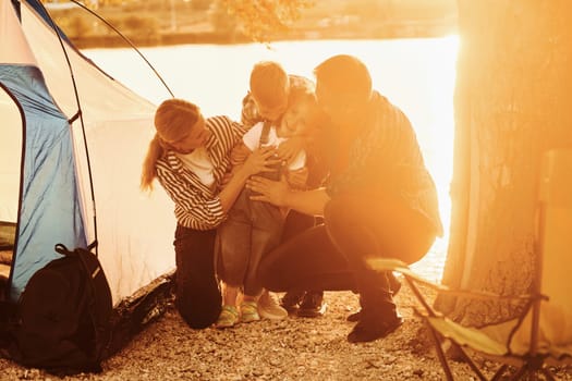 Beautiful sunlight. Family of mother, father and kids is on the camping.