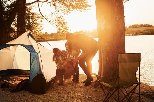 Active time spending. Family of mother, father and kids is on the camping.