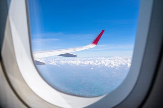 Aerial, earth, land, cloud with airplane wing from airplane window.