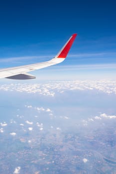 Aerial, earth, land, cloud with airplane wing from airplane window.