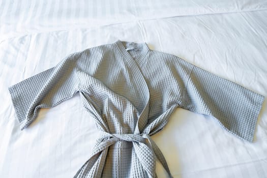 Gray color Bathrobe on a white bed.
