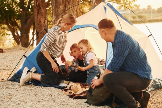 Sitting on the ground. Family of mother, father and kids is on the camping.