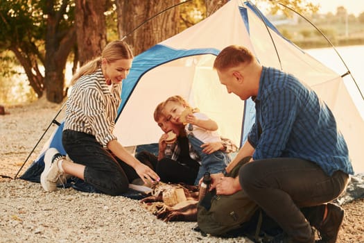 Sitting on the ground. Family of mother, father and kids is on the camping.