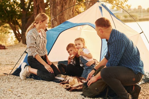 Sitting on the ground. Family of mother, father and kids is on the camping.