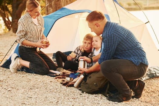 Active time spending. Family of mother, father and kids is on the camping.