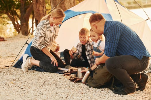 Active time spending. Family of mother, father and kids is on the camping.