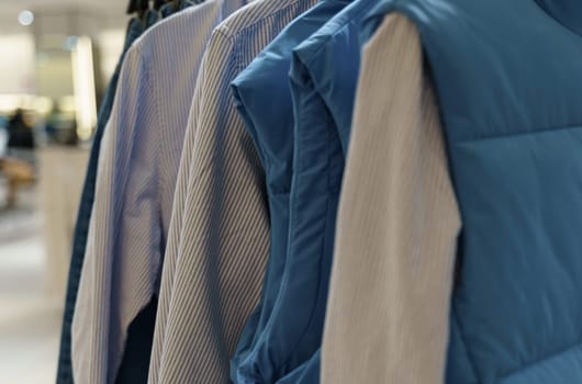 Sleeveless shirts and jackets hang on hangers in the store.