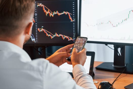 Graphs and diagrams. Young businessman in formal clothes is in office with multiple screens.