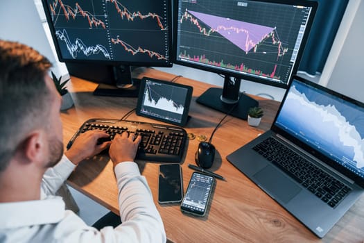 Close up view. Young businessman in formal clothes is in office with multiple screens.