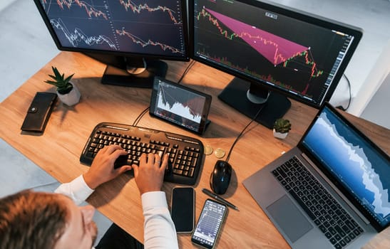 Close up view. Young businessman in formal clothes is in office with multiple screens.