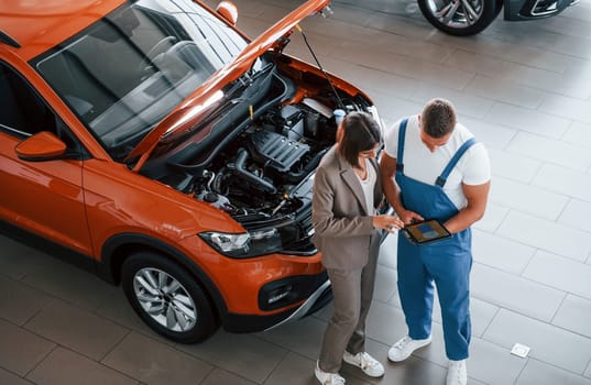 Showing results of work. Man repairing woman's automobile indoors. Professional service.