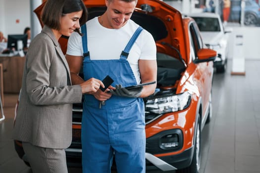 Two people. Man repairing woman's automobile indoors. Professional service.