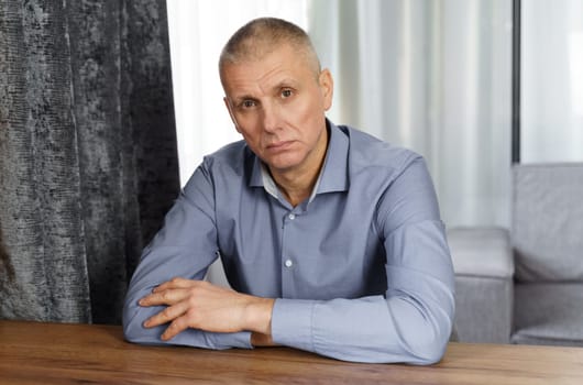 A portrait of a serious man holding his hand on his face and looking into the cell. Close-up.