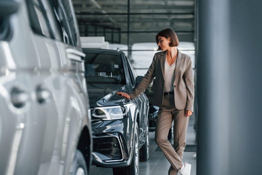 Modern technology. Woman is indoors near brand new automobile indoors.