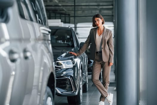 Modern technology. Woman is indoors near brand new automobile indoors.