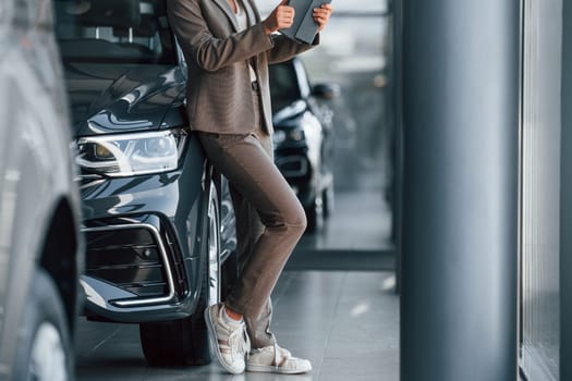 Particle view. Woman is indoors near brand new automobile indoors.