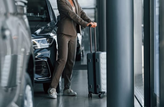 Particle view. Woman is indoors near brand new automobile indoors.