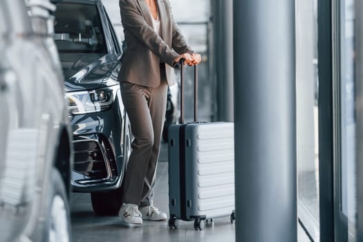 Particle view. Woman is indoors near brand new automobile indoors.